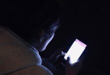 Людина гортає стрічку новин у смартфоні пізно ввечері