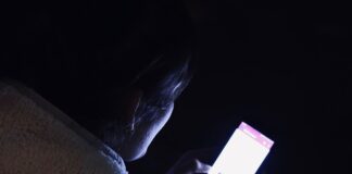 A person scrolls through the news feed on a smartphone late at night
