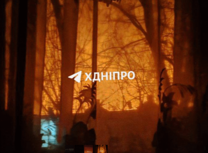 Нічний Дніпро під час атаки БПЛА, в небі видно спалахи роботи ППО.