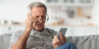 A pensioner looks at his smartphone with a warning about fraudulent messages