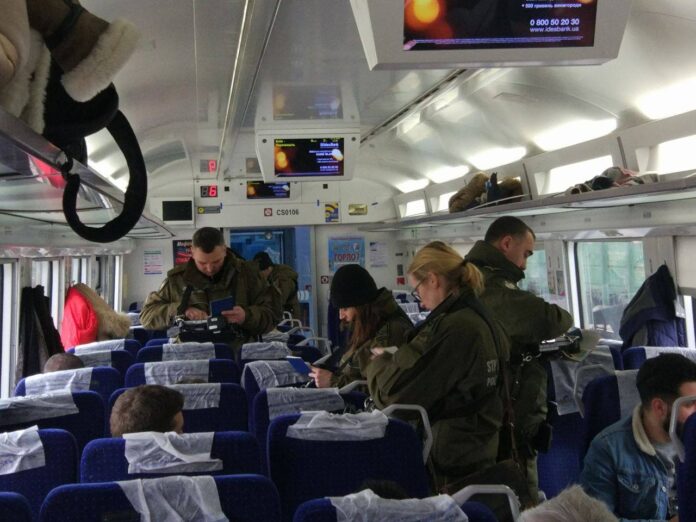 Border guards and customs officers control documents in a train