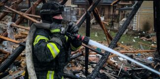 Рятувальник ДСНС гасить пожежу серед руїн будинку після російського удару