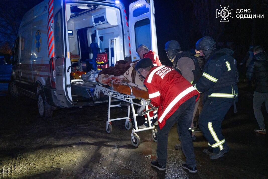 Рятувальники переносять постраждалу людину до карети швидкої допомоги після нічної атаки дронами в Одесі