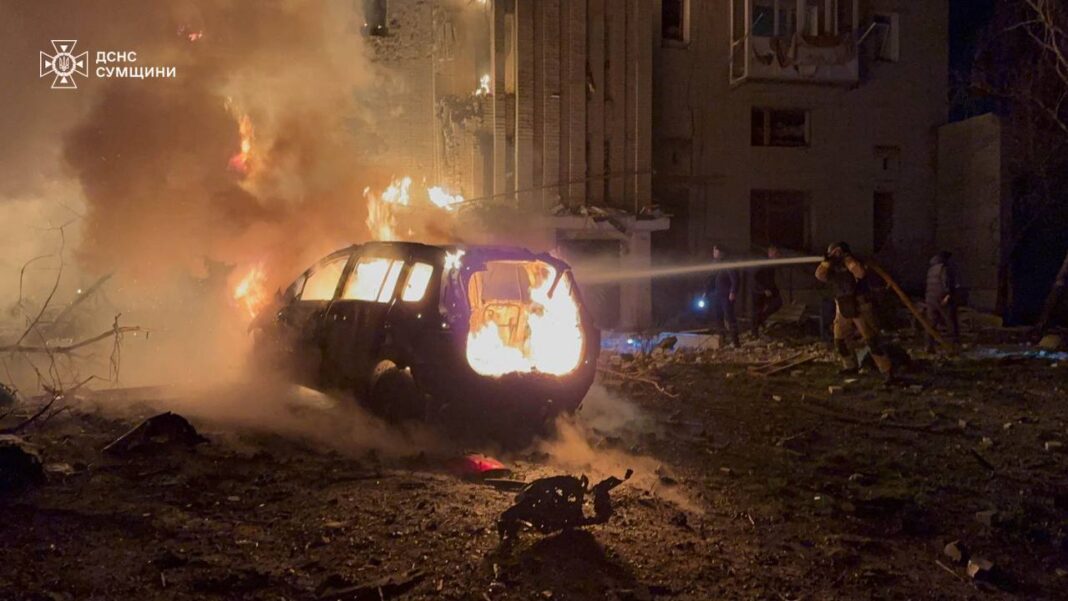 Рятувальники гасять пожежу біля палаючого автомобіля та зруйнованої багатоповерхівки