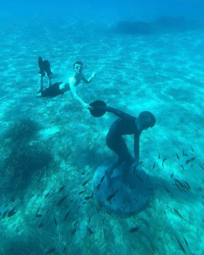 photo_2025-12-09_16-14-04 Плавець під водою поруч із встановленою на морському дні великою статуєю у вигляді персонажа Скідварда.