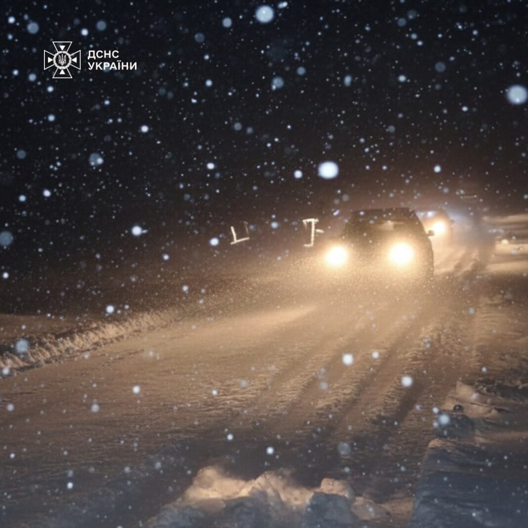 Cars drive on a snowy road during bad weather in Ivano-Frankivsk region