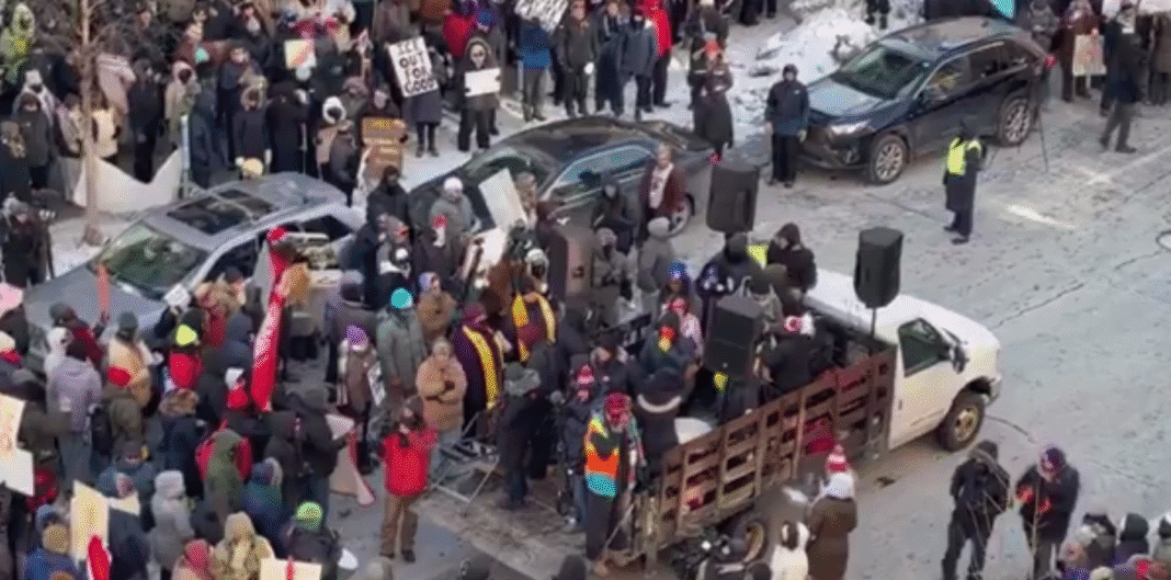 Screenshot_2 Велика група протестувальників на вулиці в зимовий день із плакатами