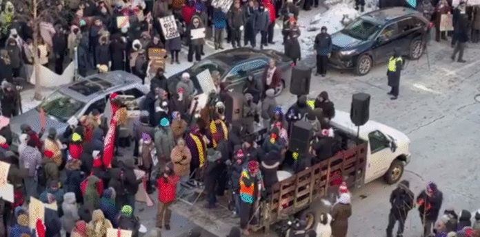 Велика група протестувальників на вулиці в зимовий день із плакатами