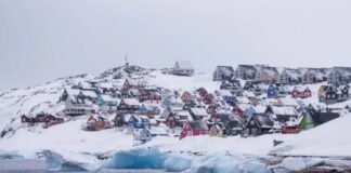 Houses in Greenland against the backdrop of the Arctic coast and glaciers