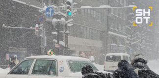 People push a car during a heavy snowfall in Japan