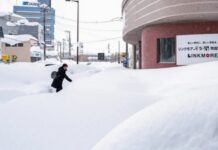 Людина пробирається крізь глибокий сніг у місті на півночі Японії