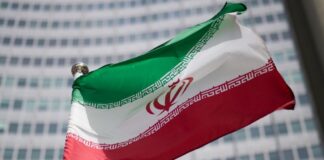 Іран заявив про «хороший початок» переговорів зі США Державний прапор Ірану на тлі урядової будівлі