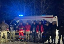 Затримані чоловіки біля автомобіля швидкої допомоги на кордоні