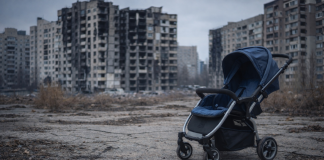 Порожня дитяча коляска на тлі міста в Україні