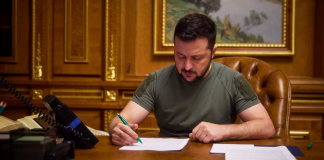 Zelenskyy imposes sanctions against Russian and Iranian military-industrial complexes Volodymyr Zelenskyy signs documents at his desk.