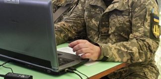 Ukrainian IT specialist in military uniform working at a computer