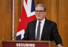 Стармер обіцяє жорстку міграцію Кір Стармер виступає перед прихильниками на тлі британського прапора.