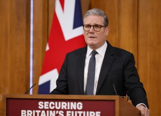 Starmer promises tough migration Keir Starmer speaks to supporters against the backdrop of the British flag.