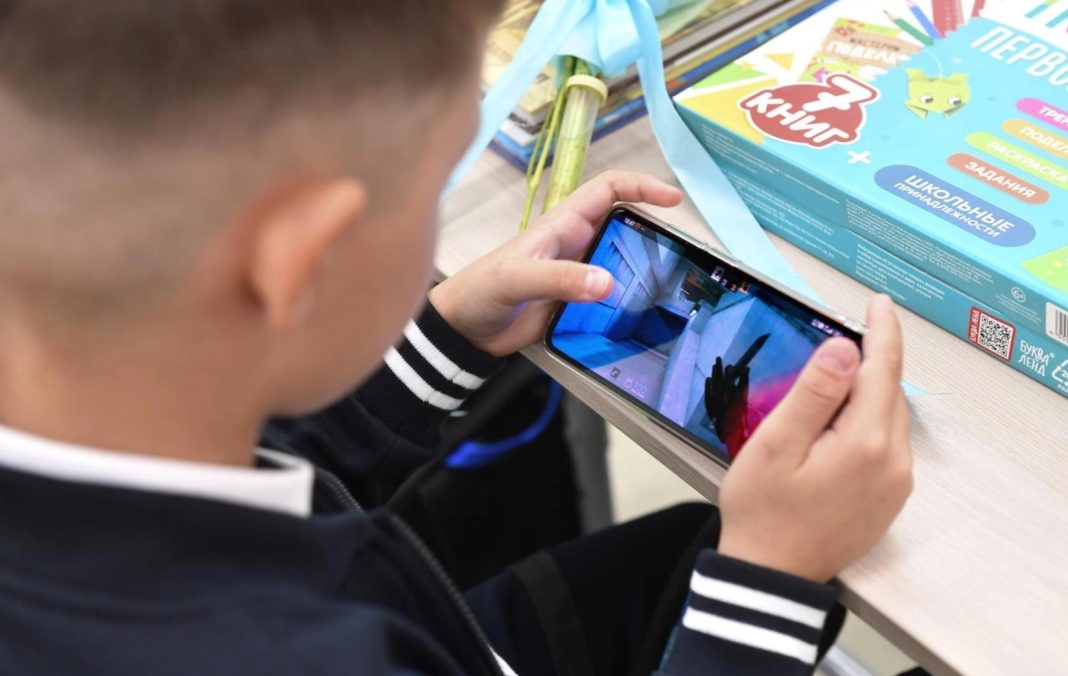 Ученьтримає смартфон у класі під час уроку