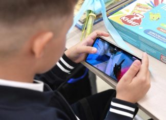 Council prepares smartphone restrictions for students A student holds a smartphone in the classroom during a lesson