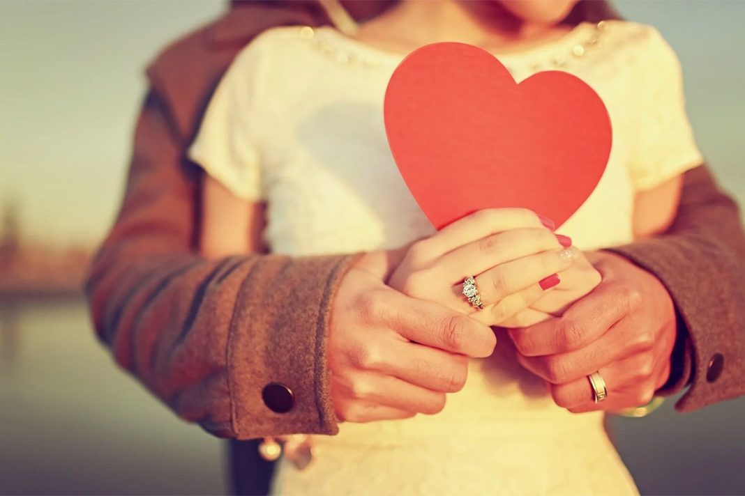 fall-in-love Пара тримає руки на фоні заходу сонця