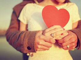 Пара тримає руки на фоні заходу сонця