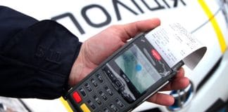 Поліцейський виписує штраф водію на дорозі України.