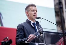 Peter Magyar speaks at a press conference, with the Tysa party logo in the background«