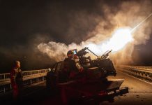 Ukrainian soldiers against the backdrop of an air defence system during a night attack