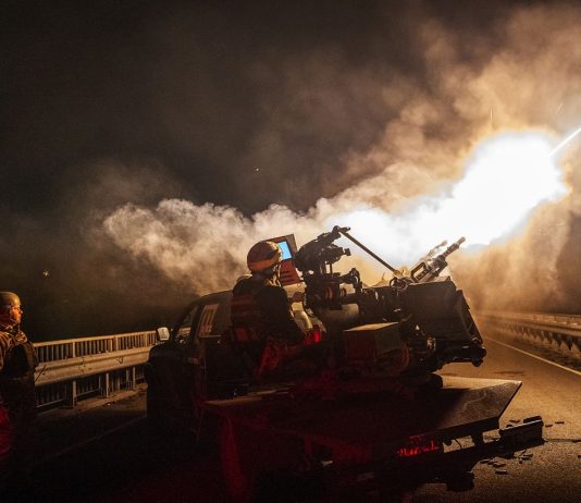 Ukrainian soldiers against the backdrop of an air defence system during a night attack