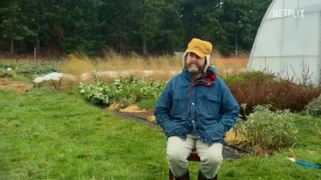 zach-g-1-e1773947450660 Зак Галіфіанакіс у студії з кімнатними рослинами під час зйомок шоу.