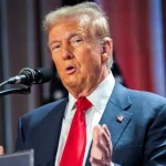 Donald Trump during a press conference, with the US flag in the background