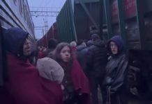 Пасажири стоять біля потяга під час повітряної тривоги на залізничній станції.