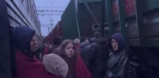 Пасажири стоять біля потяга під час повітряної тривоги на залізничній станції.