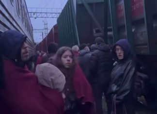 Passengers stand near a train during an air raid alert at a railway station.