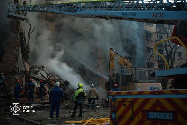 Firefighters work near a destroyed building after Russian attack on Kyiv