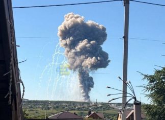 A huge column of smoke from a powerful explosion against a blue sky and countryside landscape in Belgorod