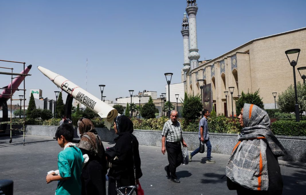 People walk past a symbolic model of an Iranian missile on a street in Tehran, Iran, on 11 June 2026.