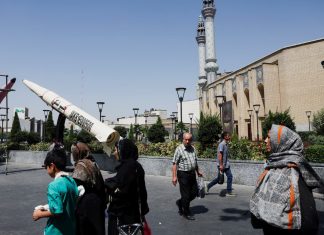 People walk past a symbolic model of an Iranian missile on a street in Tehran, Iran, on 11 June 2026.
