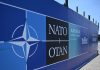 Логотип НАТО на фоні військової техніки