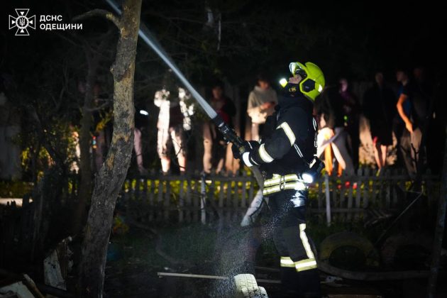 A SES firefighter works at the site of a UAV strike in Odesa at night