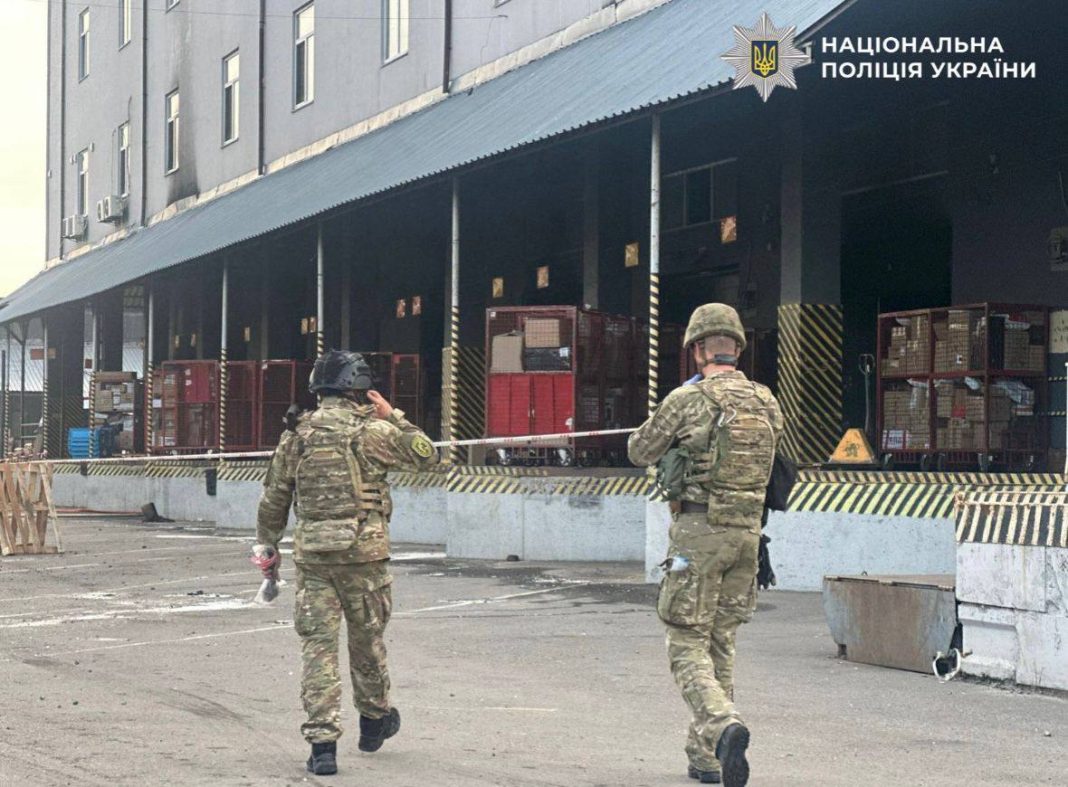 Explosives experts and law enforcement officers in camouflage work in the cordoned-off area of a postal terminal in Kyiv after the explosion.