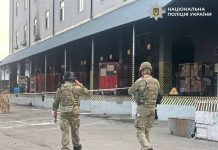 Explosives experts and law enforcement officers in camouflage work in the cordoned-off area of a postal terminal in Kyiv after the explosion.