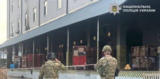 Explosives experts and law enforcement officers in camouflage work in the cordoned-off area of a postal terminal in Kyiv after the explosion.
