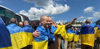 Звільнені українські захисники повертаються на рідну землю в оточенні підтримки та прапорів.