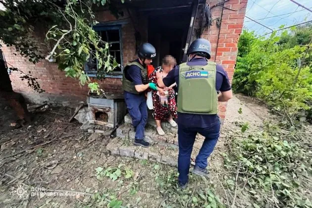 Рятувальники евакуюють постраждалу жінку з пошкодженого будинку після російського удару на Дніпропетровщині