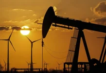Ціни на нафту зросли до місячного максимуму через ескалацію в Ормузькій протоці Нафтова насосна установка на тлі вітрових електростанцій під час заходу сонця