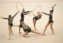The gymnasts are performing a group routine with hoops