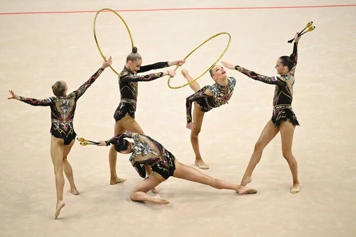 36_main-v1782488054 The gymnasts are performing a group routine with hoops