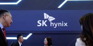 SK Hynix has raised $26.5 billion on the Nasdaq to expand its AI chip production The SK Hynix logo against a backdrop of stock market charts.